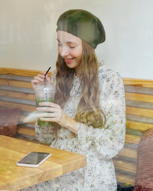 Free Photo woman sitting at table holding smoothie