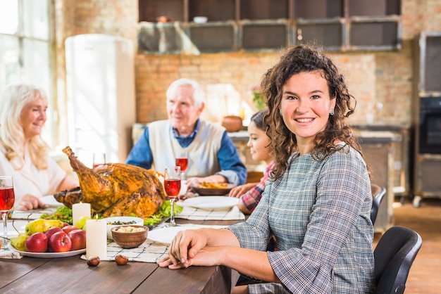 Woman sitting at table near girl and elderly people