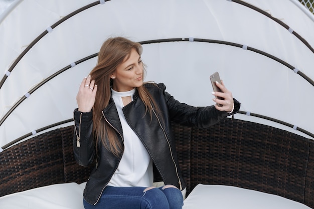 Free photo woman sitting in a wicker armchair doing an auto photo