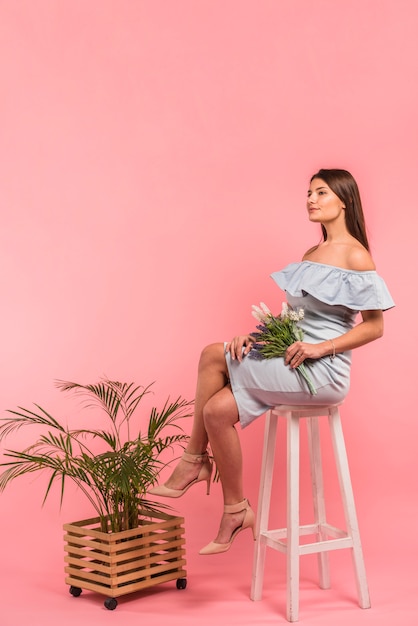 Woman sitting with flowers bouquet on chair 