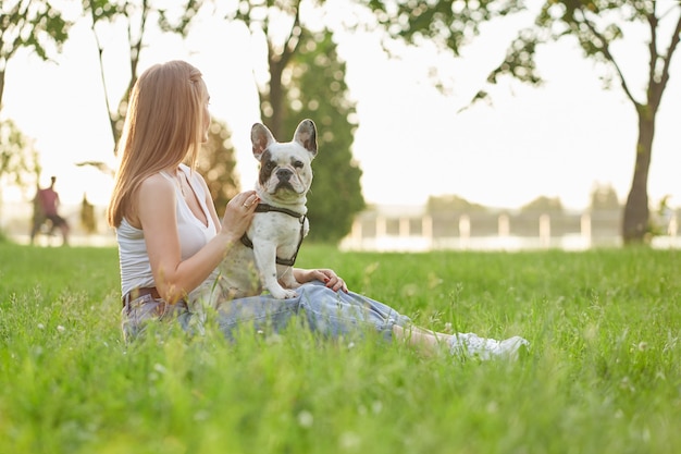 Woman sitting with french bulldog on grass