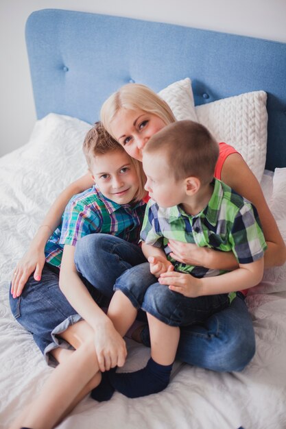 Woman sitting with her children on the bed