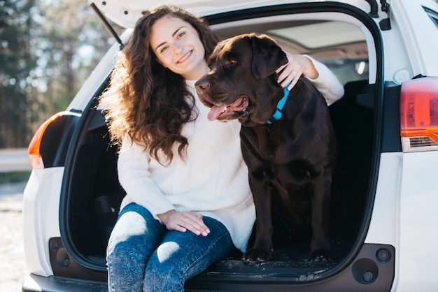 Free photo woman sitting with her dog in open trunk