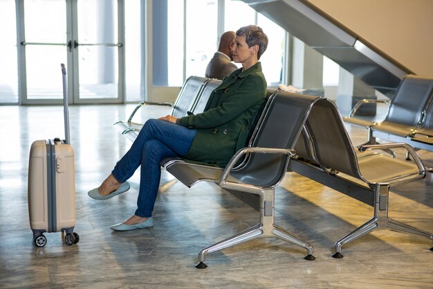 Woman sitting with luggage at waiting area