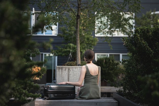 Woman sitting with a suitcase in the park