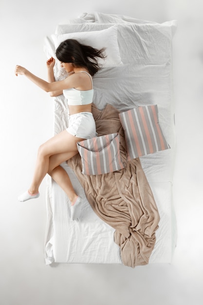 Woman sleeping and resting alone in her bed, dreaming. Top view from above