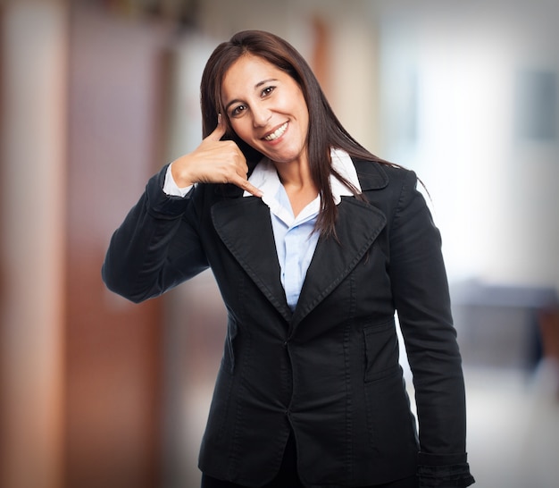 Free photo woman smiling with suit making as she calls on the phone with her hand