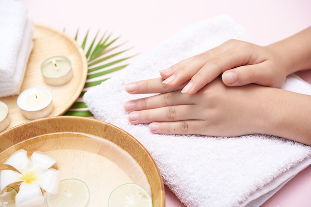 Free Photo woman soaking her hands in bowl of water and flowers, spa treatment and product for female feet and hand spa, massage pebble, perfumed flowers water and candles, relaxation. flat lay. top view.