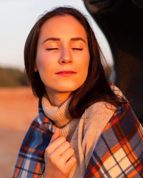 Woman soaking up the sun with blanket on while out in nature