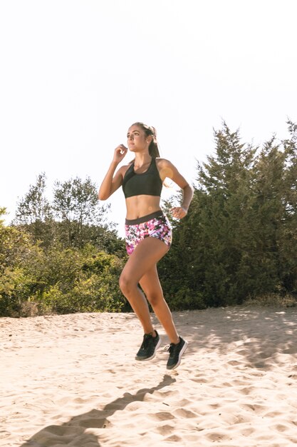 Woman in sportswear jogging on the sand 