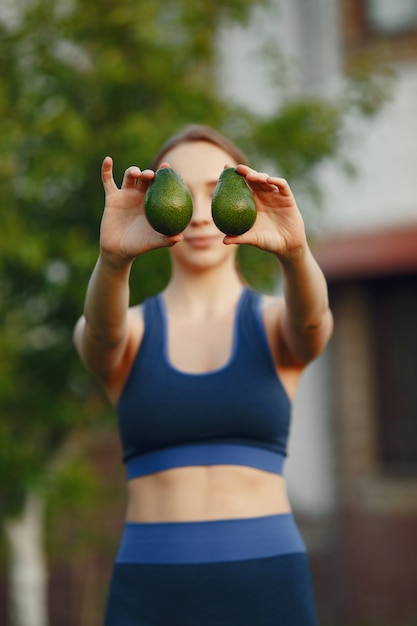 Woman in a sportwear holds a fruits