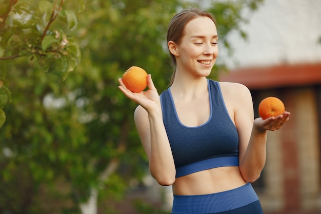 Free photo woman in a sportwear holds a fruits