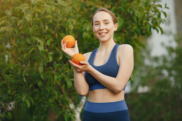 Free photo woman in a sportwear holds a fruits