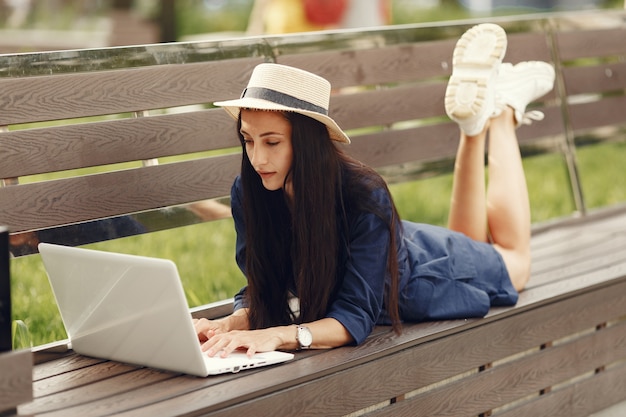 Woman in a spring city. Lady with a laptop. Girl sitting on a bench.