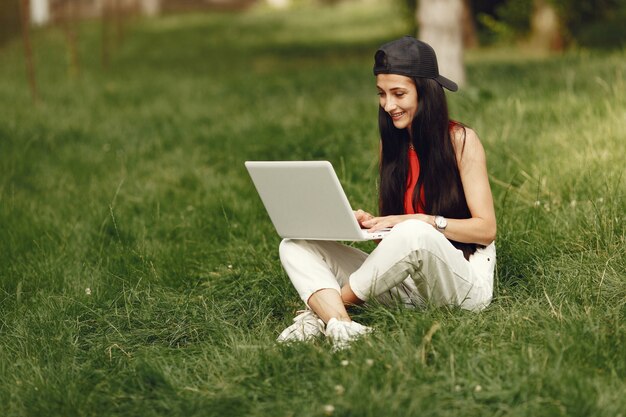 Woman in a spring city. Lady with a laptop. Girl sitting on a grass.