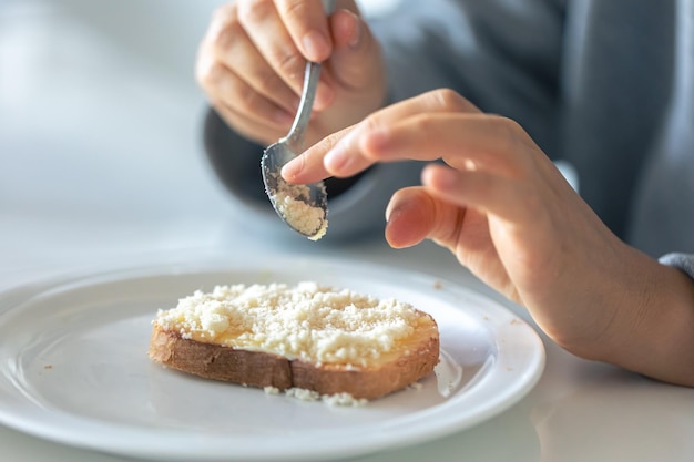 Free photo a woman sprinkles a piece of bread with grated cheese