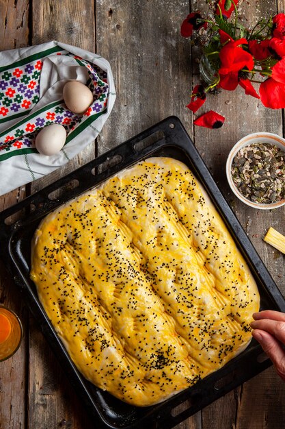 Woman sprinkling spice onto dough before baking top view.