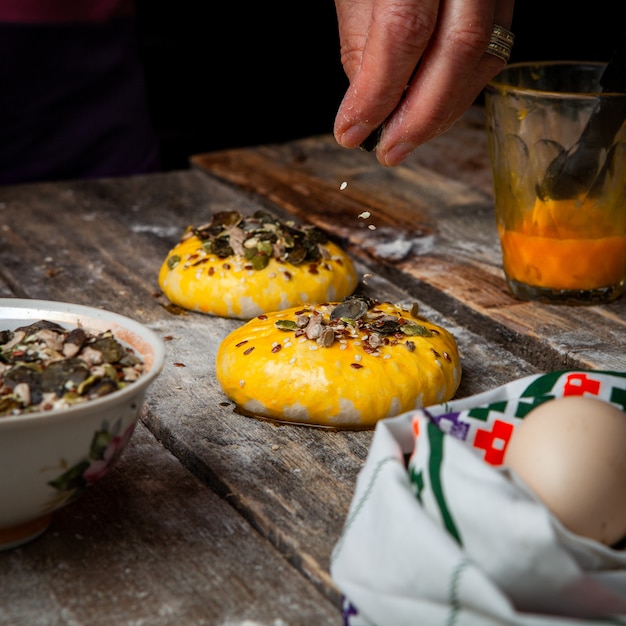 Free Photo woman sprinkling spices with hands onto dough side view