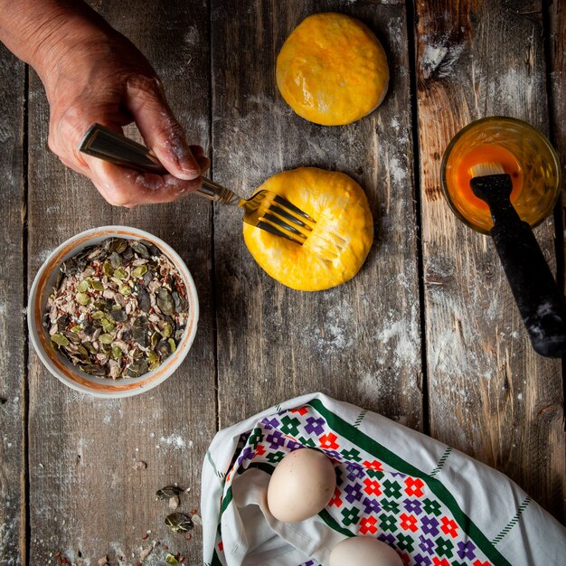 Woman squashing dough with fork before baking top view.