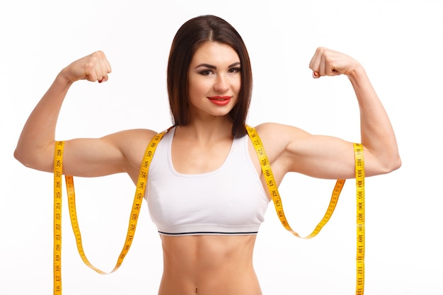 Free photo woman squeezing both biceps and a tape measure