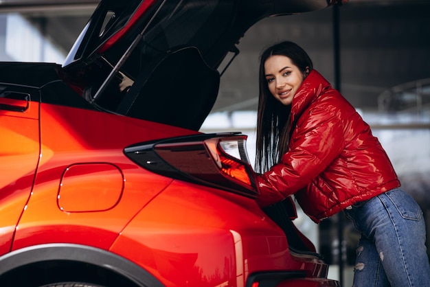 Woman standing by her new red car