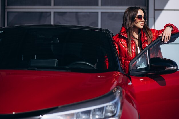 Woman standing by her new red car