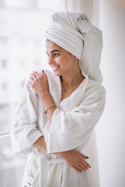 Free photo woman standing by the window in bathrobe