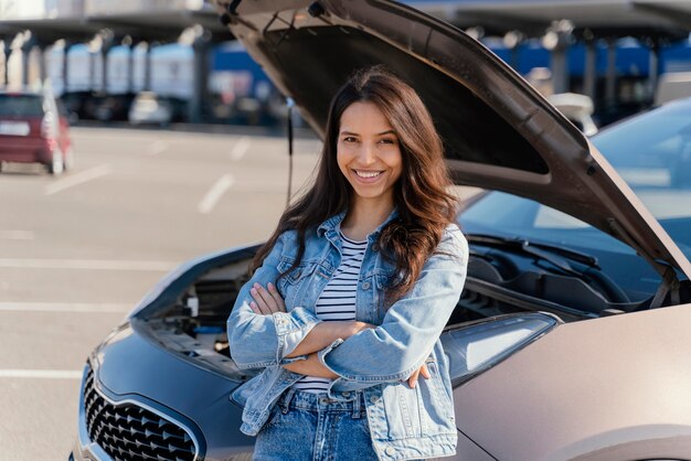 Woman standing next to her broken car