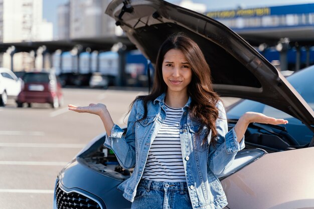 Woman standing next to her broken car