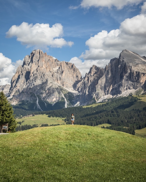 Free Photo woman standing on a hill with the plattkofel mountain as backgound in compatsch italy