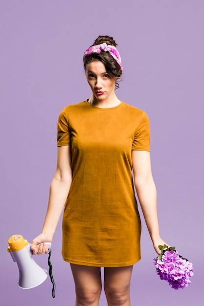 Free photo woman standing and holding megaphone and flower front view