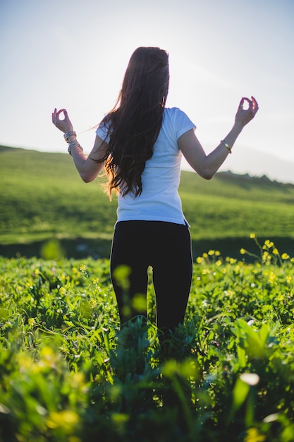 Woman standing and meditating in green grass