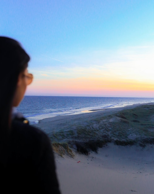 Free photo woman standing on seashore during golden hour