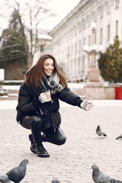 Woman standing on the street surrounded by pigeons