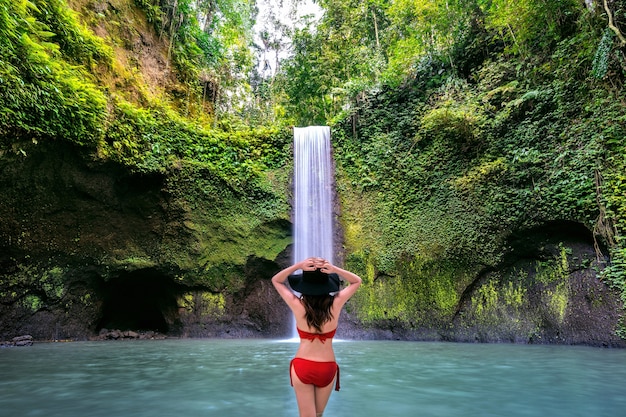 Free Photo woman standing in tibumana waterfall in bali island, indonesia