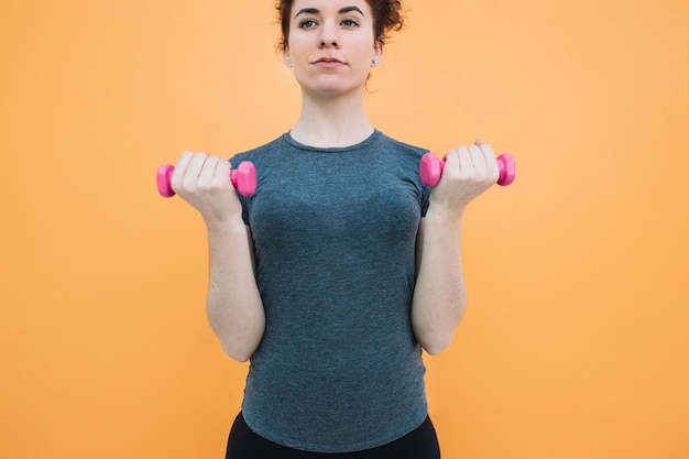 Free Photo woman standing with dumbbells