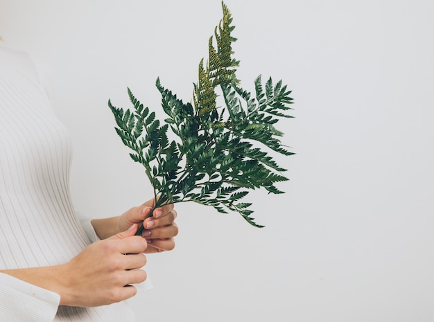 Woman standing with fern leaves 