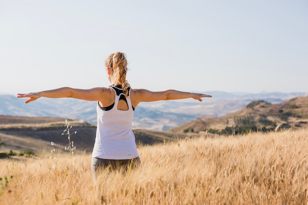 Free photo woman standing with hands apart in grass