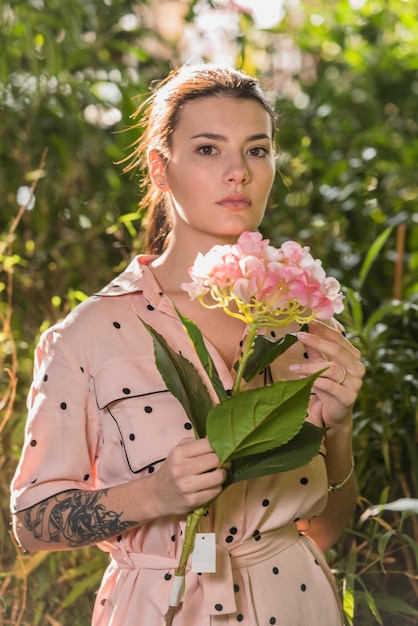 Free photo woman standing with pink flower in hand