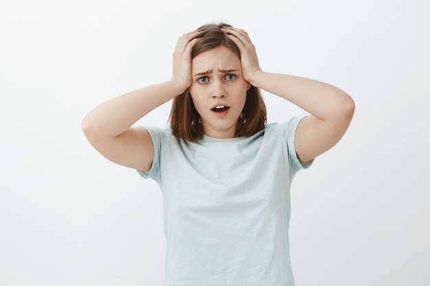 Woman starting panic cannot meet deadline in time. Portrait of hopeless upset and gloomy concerned cute girl holding hands on hair opening mouth and frowning compaining feeling troubled and nervous