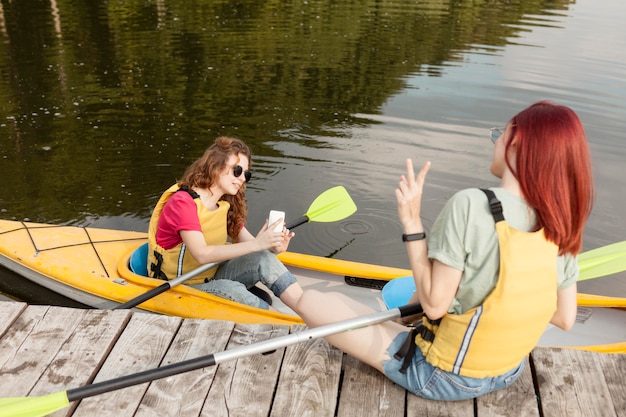 Free Photo woman staying in kayak and taking photos of friend