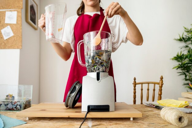 Woman stirring torned paper in blender