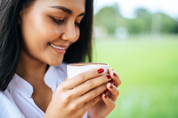 woman stood happily drinking coffee on the meadow