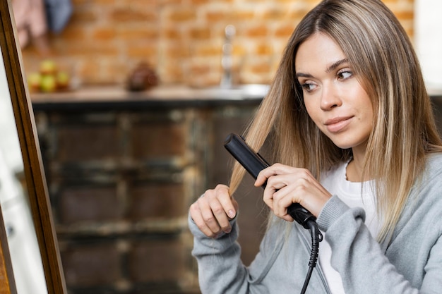 Woman straightening her hair at home