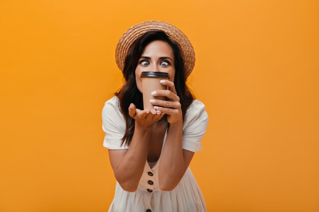 Woman in straw hat looks adoringly at glass of tea