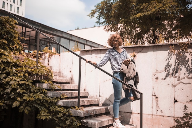 Free photo woman in street wear going down on steps