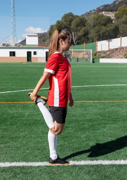 Free photo woman stretching leg on football field