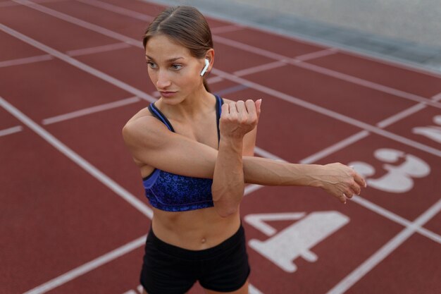 Woman stretching on running track high angle