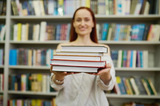 Woman stretching stack of books to camera