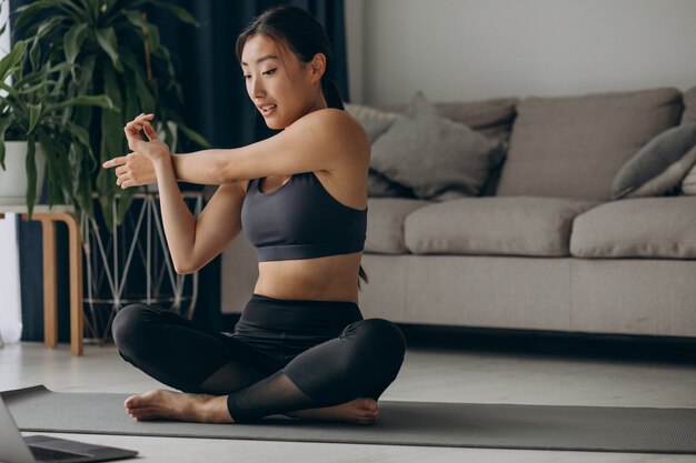 Woman stretching on yoga mat at home